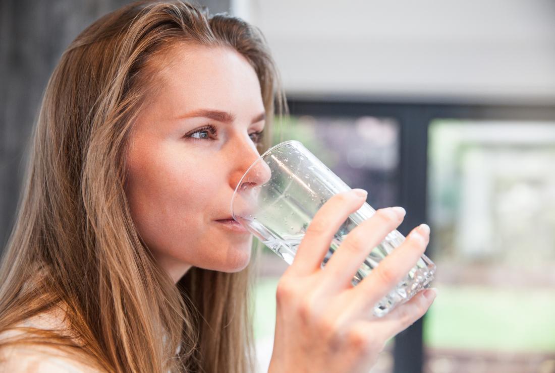 a woman drinking water as a Home remedies for bad breath